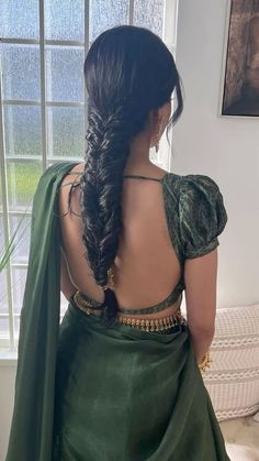 the back of a woman's green dress, with her hair in a braid