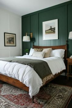 a bedroom with green walls and white bedding, rugs and lamps on either side of the bed