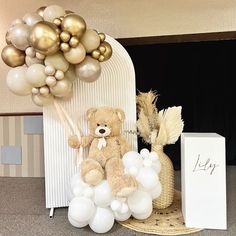 a teddy bear sitting on top of a basket next to balloons