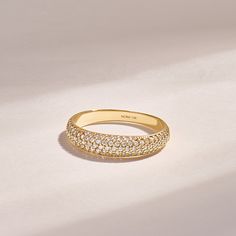 a yellow gold ring with rows of diamonds on the outside and inside, sitting on a white surface