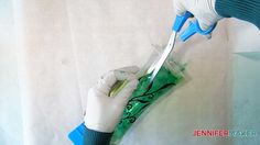 a person with white gloves cutting something green