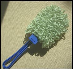 a green and blue mop laying on top of a tan surface