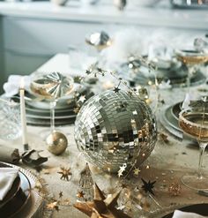 a table topped with plates and silverware covered in confetti, stars and disco balls