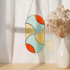 a vase with dried flowers in it next to a wall hanging ornament on a shelf