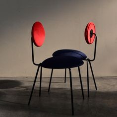 two blue and red chairs sitting next to each other on top of a cement floor