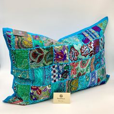 a blue pillow with colorful patchwork on it and a tag in front of it