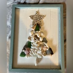 a shadow box with seashells in it and a star hanging from the top