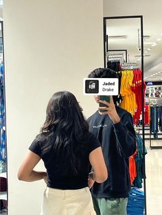 a man and woman standing in front of a clothing store holding up a sign that reads,