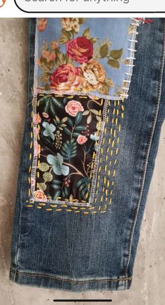 a pair of jeans with flowers and leaves on them, sitting next to each other