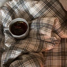 a cup of tea is sitting on a plaid blanket