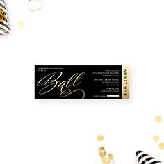 a black and gold party ticket with confetti on the table next to it