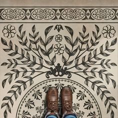 a pair of brown shoes sitting on top of a tiled floor next to a wall