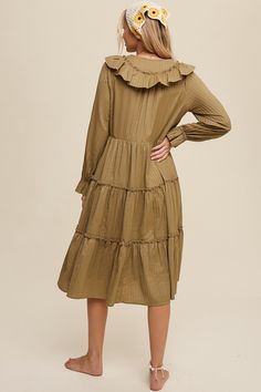 a woman wearing a brown dress with long sleeves and tiered ruffles on the bottom