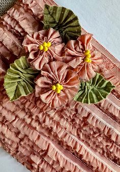 pink and green flowers are placed on the edge of a piece of fabric that has ruffled edges