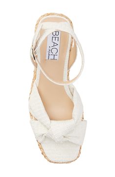 A knotted vamp accent brings modern dimension to a boho-cool sandal lifted by a raffia-wrapped platform and integrated wedge heel. 3" heel; 1" platform Adjustable ankle strap with buckle closure Cushioned footbed with arch support Synthetic upper, lining and sole Imported Vacation Sandals With Wrapped Heel And Ankle Tie, Chic White Wedge Sandals For Beach Season, Cream Wedge Sandals With Removable Insole For Beach, Adjustable Cream Wedge Sandals For Beach, Cream Synthetic Wedge Sandals For Beach Season, Adjustable Fit Cream Wedge Sandals For Beach, White Straw Wedge Sandals, White Straw Wedge Sandals With Woven Sole, White Ankle Tie Sandals For Summer