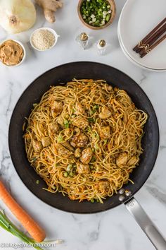 a pan filled with noodles and meatballs on top of a white marble countertop