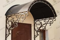 an arched metal door with a black awning over it and a mirror on the wall