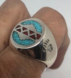 a man's hand holding a ring with a blue and red design on it