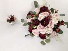 a bridal bouquet and boutonniere on a white surface