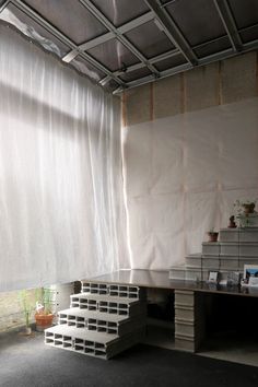 an empty room with some stairs in front of the window and white curtains on the wall