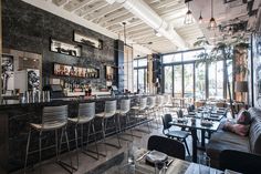 a bar with lots of chairs and tables in front of large windows, next to a couch