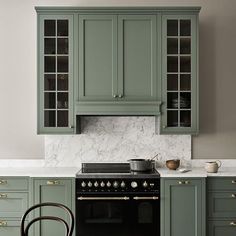 a kitchen with green cabinets and white marble counter tops, an oven in the center