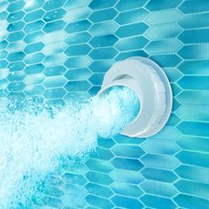 a blue tiled swimming pool with water coming out of the faucet and splashing on it