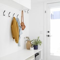 a white entryway with coat hooks and plants