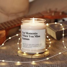 a lit candle sitting on top of a wooden table next to a string of lights