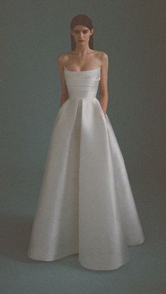 a woman in a white dress standing against a gray background