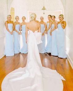 a bride and her bridesmaids in light blue dresses are posing for the camera