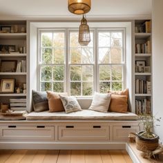 a window seat with bookshelves in front of it and a lamp hanging from the ceiling