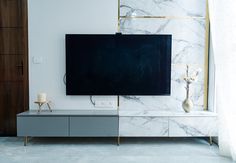 a flat screen tv sitting on top of a white cabinet next to a vase with flowers