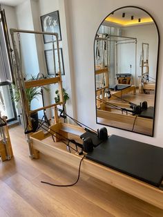 an exercise room with mirrors and equipment on the wall, in front of a wooden floor