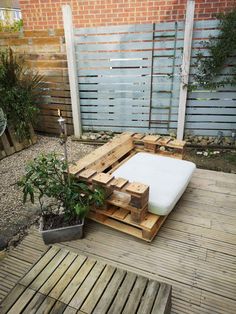 a bed made out of wooden pallets on a deck in a back garden area