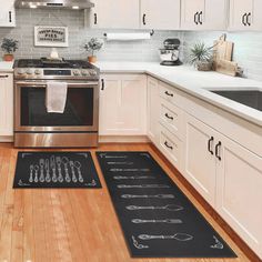 a kitchen with white cabinets and stainless steel stove top oven next to a black mat that has utensils on it