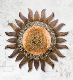 a decorative metal sunflower on a white wall with brown and orange designs in the center