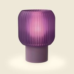 a purple table lamp sitting on top of a white floor next to a gray wall