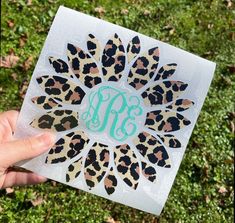 a person holding up a card with the letter m on it in front of some grass