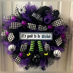 a purple wreath with black and white checkered stockings on it that says, it's good to be witches