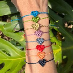 a woman's arm with multicolored bracelets and hearts on the wrist