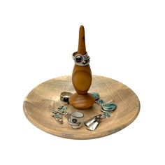 a small wooden object on top of a plate with other items around it, including an owl figurine