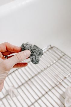 a person holding something in their hand near a wire rack