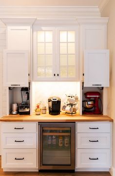 a kitchen with white cupboards and appliances on the counter top, including a coffee maker