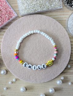 a bracelet that says smile on it with beads and pearls around the bead area