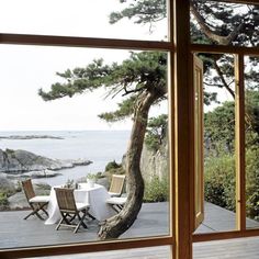 an open window shows the ocean and table with chairs on it in front of a wooden deck