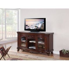 an entertainment center with a flat screen tv on it's stand in front of a window