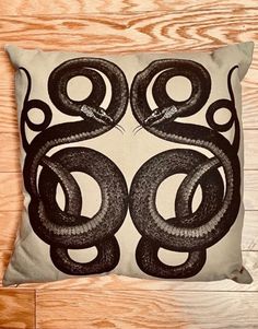 a black and white pillow with an image of a snake on the front, sitting on top of a wooden floor