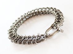 This bracelet is hand woven link by link. It is made using the finest stainless steel we can get our hands on and finished with top quality clasps. Heavy duty and built to last, this chain will not rust or fall apart. Now available with your choice of clasp.________________________________________________________________________________________*16 gauge stainless steel chain in King's Link weave*Top quality clasps are very secure*Small fits wrists up to 6.5 inches (16.5 cm)*Medium fits wrists up Stainless Steel Chain Link Jewelry With Jump Ring, Handmade Stainless Steel Link Chain Bracelet, Stainless Steel Chain Link Jewelry With Hooks, Handmade Stainless Steel Link Bracelets, Silver Stainless Steel Bracelets With Hook And Links, Handmade Link Bracelets In Stainless Steel, Jewelry For Him, Leather Eyeglass Cases, Mens Jewelry Box