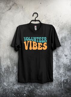 "Elevate your volunteer spirit with our \"Volunteer Vibes\" unisex t-shirt! Designed in a nostalgic retro font, this tee is not only stylish but also carries a powerful message of community support and giving back. 🌟 Key Features: High-quality, soft, and comfortable fabric for everyday wear. Classic unisex fit that suits all body types. \"Volunteer Vibes\" is designed in a charming retro font for a vintage feel. Perfect for volunteers, charity events, community gatherings, or casual wear. A gre Volunteer Shirt, Volunteer Gifts, Community Support, Charity Events, Group Shirts, Retro Font, Giving Back, Casual Tee, Trendy Colors